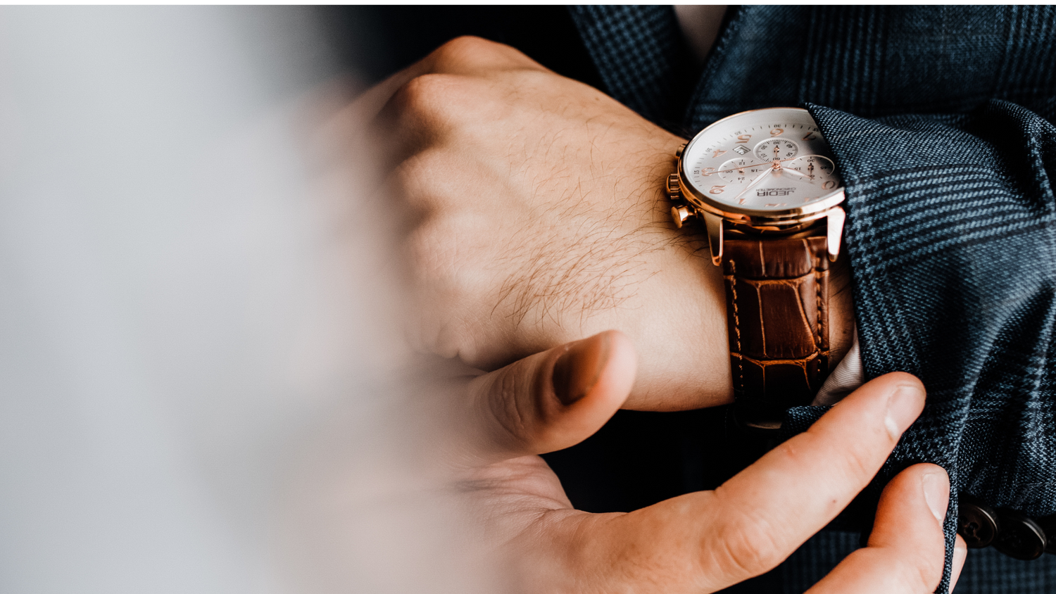 a man adjusting his cuff to reveal his wrist watch
