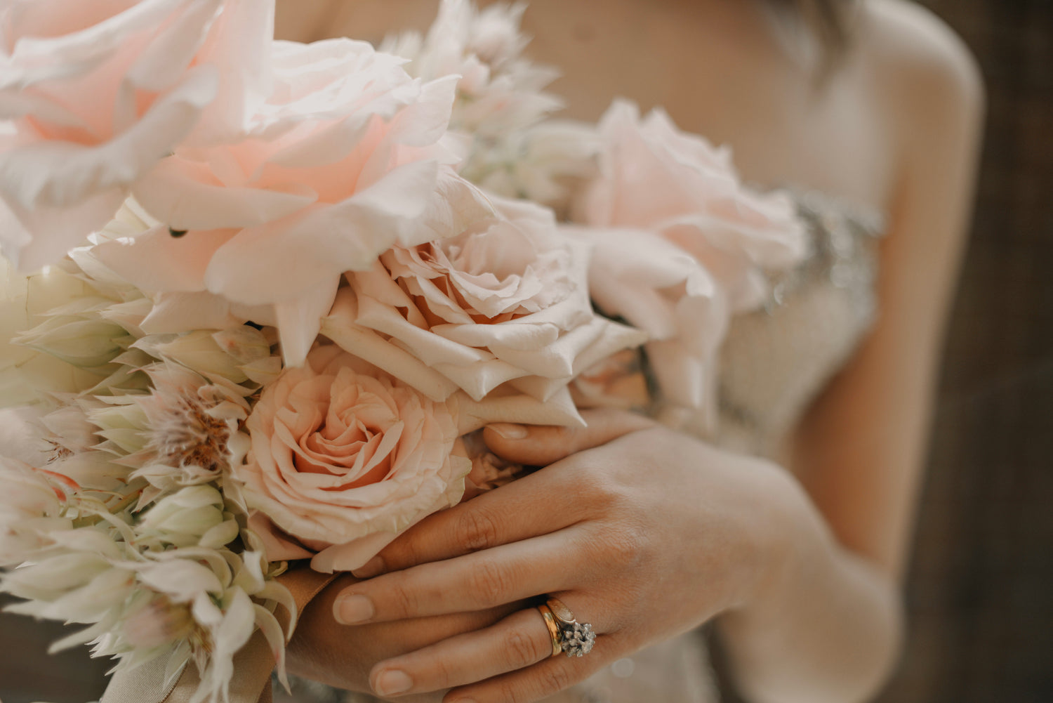 a bride holding a bunch of flowers wearing her engagement ring and wedding ring